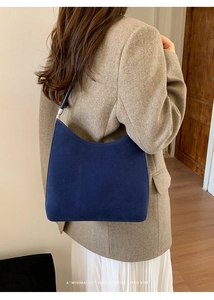 Détail du sac hobo en daim bleu marine avec boucle argentée porté avec une veste vintage