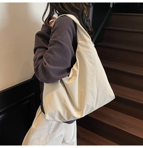 Vue détaillée du grand sac cabas en nylon crème porté par un mannequin en escalier