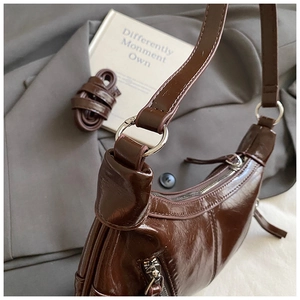 Detail of dark brown glossy underarm bag with silver hardware and dual strap options