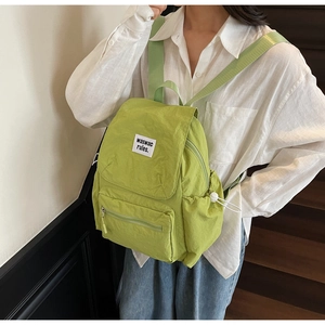 Detailed side view of light green nylon backpack with adjustable drawstring side pockets