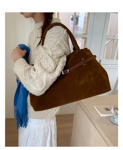Détail du grand sac cabas en daim marron avec boucle métallique porté par un modèle