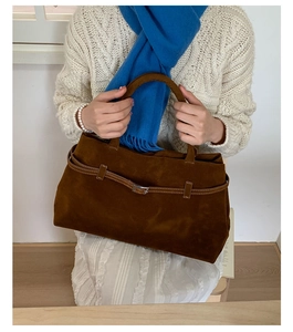 Détail d'un sac cabas en cuir mat marron foncé avec une boucle de ceinture décorative