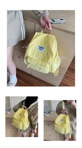 Detail of yellow nylon backpack with square brand patch and side drawstring accents