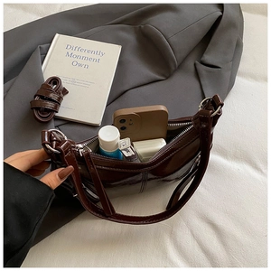 Deep brown crescent bag interior showing daily items like phone and lipstick on fabric