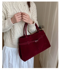 Détail du cabas en daim bordeaux avec boucle métallique décorative et sangle élégante