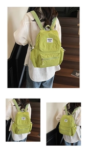 Detail view of grass green nylon backpack with front zipper pocket and drawstring side pouch
