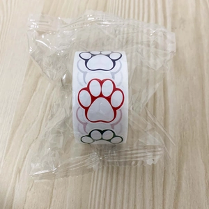 Close-up of colorful cat paw print stickers in a roll on a light wooden background