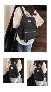 Detailed view of black nylon backpack featuring large front pocket and white logo patch
