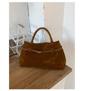 Détail du sac cabas marron mat avec boucle décorative et poignées sur bois naturel