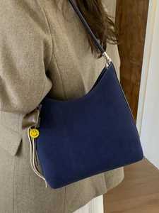 Sac hobo rétro en daim bleu marine avec breloque smiley porté par un mannequin