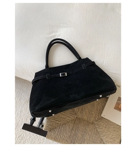 Détails du sac fourre-tout en daim noir avec boucle métallique et pieds de protection
