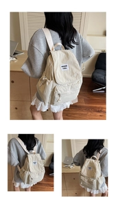 Detail view of beige canvas backpack showing flap with label and side drawstring pockets
