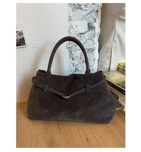 Gros plan sur un sac cabas en daim marron avec ceinture décorative et boucle en métal dorée