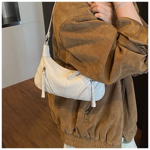 Detail of white glossy PU leather underarm bag with decorative zippers and long pullers