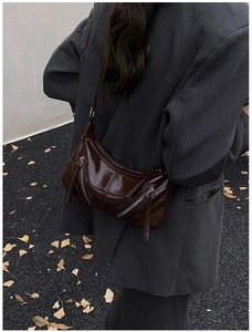 Detail of vintage coffee leather crossbody bag with tassels shown in a street style setting
