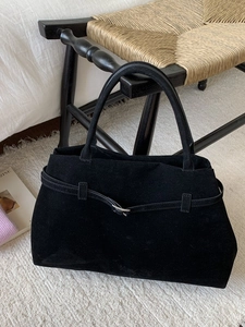 Grand sac cabas rétro en daim noir avec boucle sur une chaise, décor intérieur chic