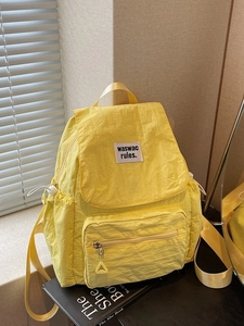 Modern bright yellow waterproof nylon backpack with spacious multi-pocket design on a desk