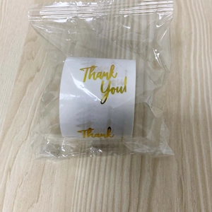 Detail of round white Thank You labels with gold foil script for gift packaging