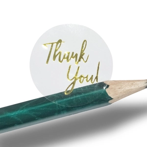 Roll of clear round stickers with gold foil Thank You text for packaging and gift sealing