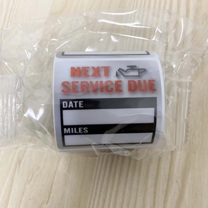 Close-up of car service reminder stickers on roll with date and miles fields