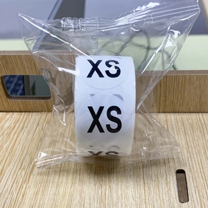Detail view of round XS size sticker labels on a roll in clear plastic packaging
