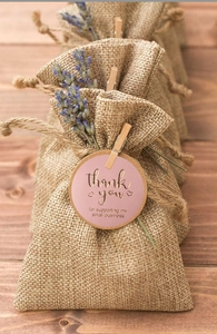Gros plan de sacs cadeaux en jute avec étiquettes roses de remerciement et mini pinces