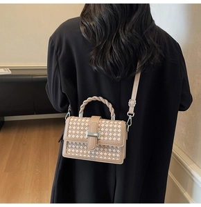 Détail d'un sac à bandoulière tressé avec poignée torsadée et boucle métallique