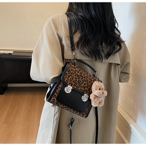 Detail of leopard print flap backpack with silver buckles and a cute plush bear charm