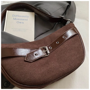 Close-up of brown suede hobo bag featuring polished leather strap and silver buckle detail