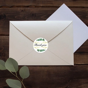Floral Thank You stickers on beige envelope with green leaves and gold curves on wood