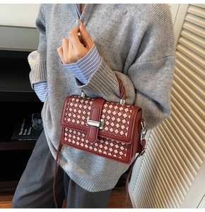 Détail macro du motif tressé rouge sur le sac bandoulière avec boucle métallique