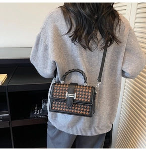 Détail du sac à bandoulière tissé avec boucle H argentée et poignée torsadée