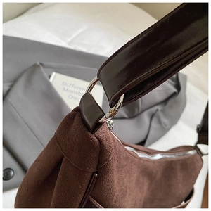 Detail of suede shoulder bag with dark leather strap and metallic ring attachment