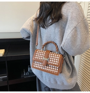 Détail du sac tissé avec boucle H en argent porté sur un pull gris chiné