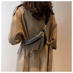 Detail of black leather crescent bag with gold rivets and long fringe tassels on a model