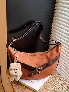 Retro caramel crescent shoulder bag with dark brown belt and plush dog charm on wood