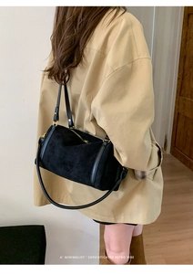 Détail du sac Boston en daim noir montrant la texture, les anses et la fermeture dorée
