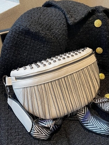 Fringe crossbody bag with silver studs and chevron strap on a black tweed coat