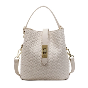 Minimalist beige woven bucket bag with gold twist lock and a detachable shoulder strap