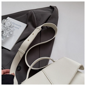 Close-up of white lychee grain leather handbag featuring decorative gold round rivets