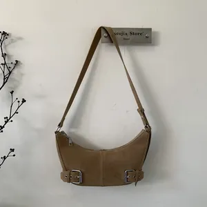 Detailed macro view of the brown suede crescent bag with silver buckles and retro hardware