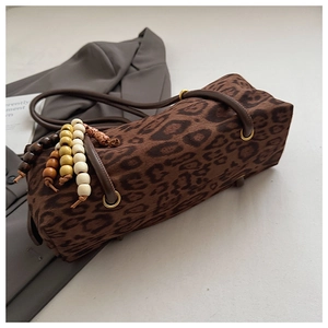 Detail of leopard print cylinder bag with colorful wooden beads and leather straps