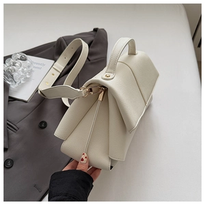 Close-up of cream lychee grain leather handbag with gold hardware and wide strap
