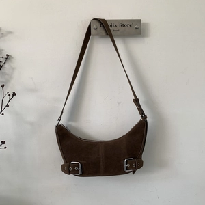 Detail view of brown suede crescent hobo bag with decorative silver buckles and strap