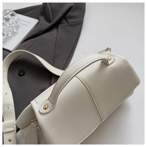 Detail of off-white lychee grain leather handbag with golden hardware and wide strap