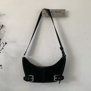 Detail view of black crescent shoulder bag featuring dual silver decorative buckles