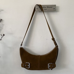 Detailed view of deep brown suede half-moon bag with silver metal buckles and retro texture
