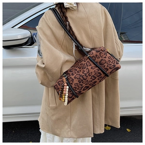 Street style view of a leopard print cylinder bag with beaded tassel and long strap