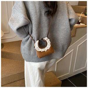 Détail d'un mini sac à bandoulière marron rétro avec broderie sur la poignée
