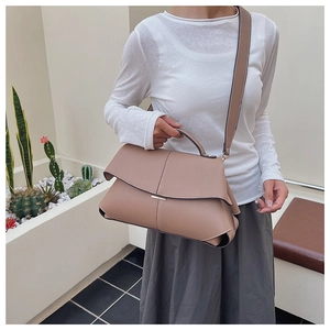 Detail of pink-brown crossbody bag featuring pebble leather texture and gold hardware